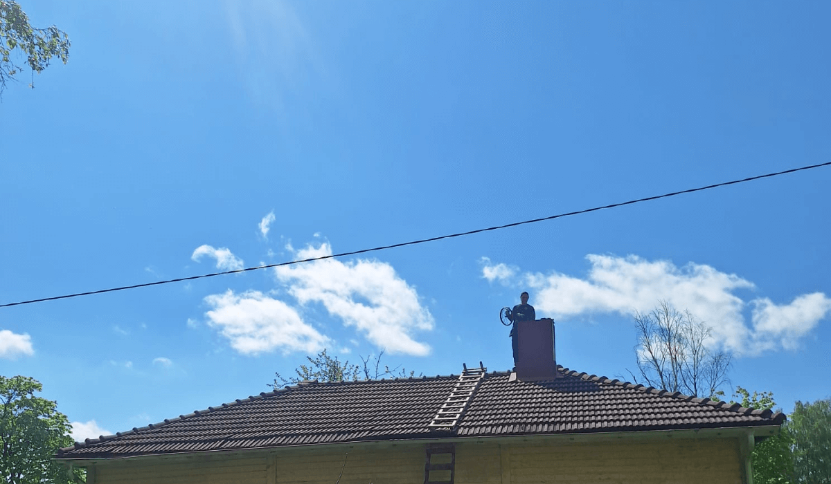 Tulisijojen kesähuolto - nuohooja talon katolla suorittamassa nuohousta